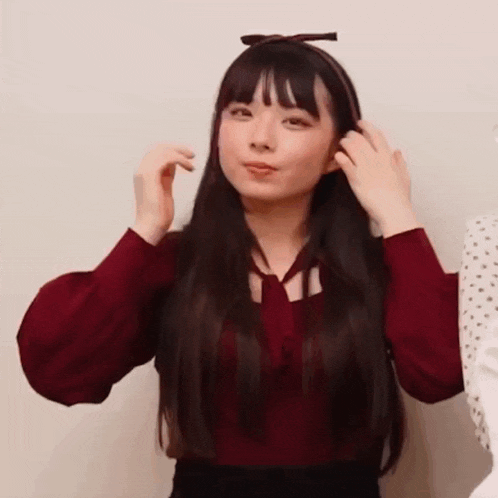 a young woman with long hair is wearing a red shirt and a headband .