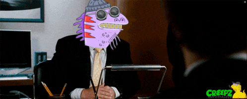 a man sitting at a desk with a purple monster head on his head