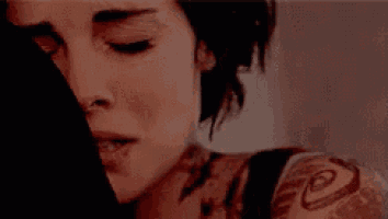 a woman with a tattoo on her arm is laying down with her eyes closed .