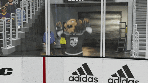 a mascot wearing a kings jersey stands in front of an adidas advertisement