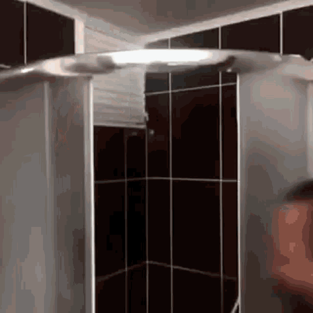 a person is standing in a shower with black tiles .