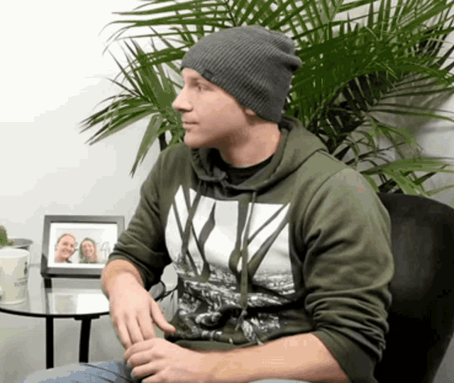 a man wearing a beanie and a hoodie with the letter v on the front