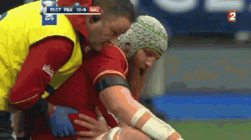 a rugby player is being helped off the field by a nurse during a game