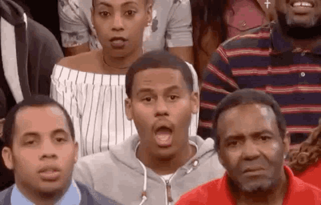 a group of people are sitting in a row with their mouths open and looking at the camera .