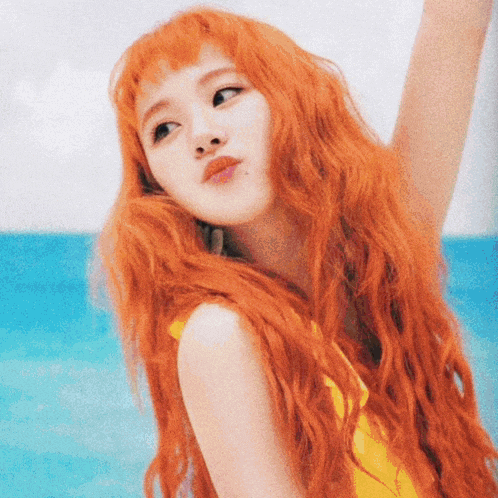 a woman with long red hair is wearing a yellow swimsuit