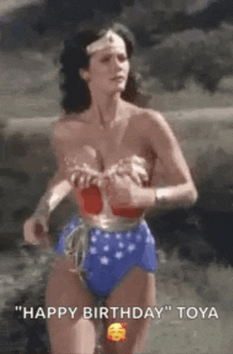 a woman in a wonder woman costume is running in a field while holding her breasts .