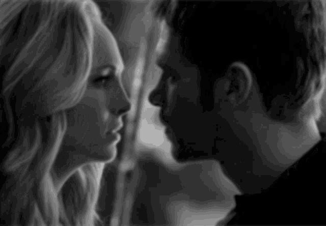 a black and white photo of a man and a woman looking into each other 's eyes