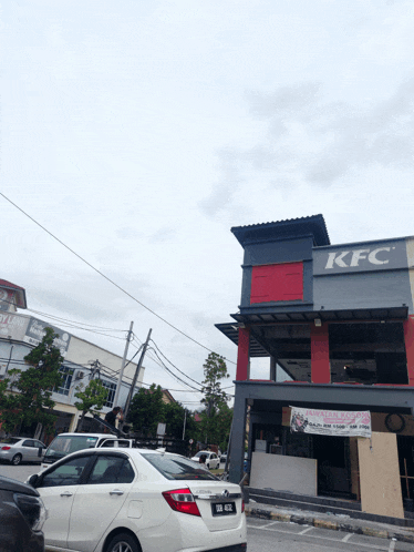 a white car is parked outside of a kfc restaurant