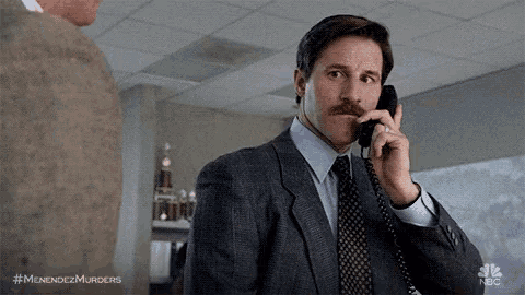 a man in a suit and tie is talking on a phone in an office .