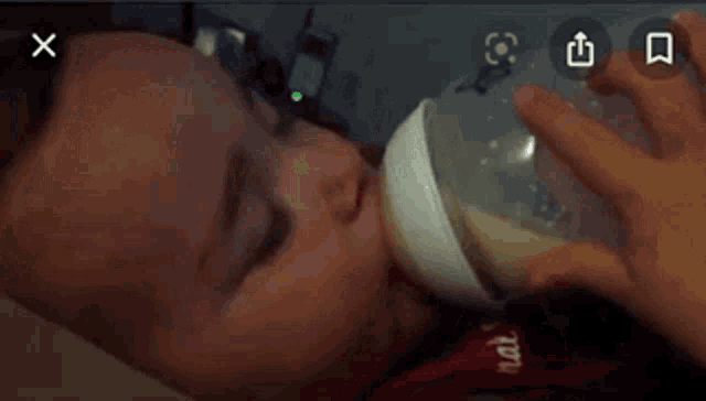 a baby is drinking from a bottle with a x on the bottom right