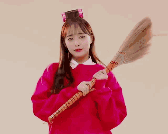 a woman in a red sweater is holding a broom in her hand .
