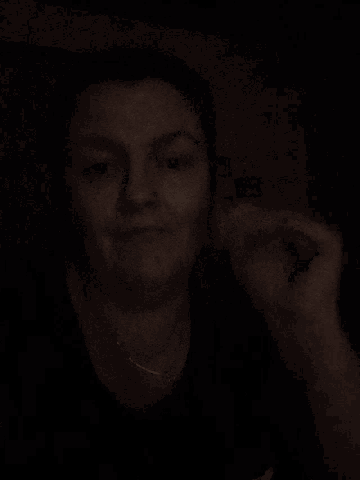 a woman 's face is shown in a dark room with her hands outstretched