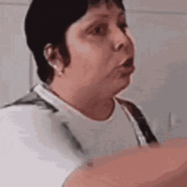 a woman in a white shirt is making a funny face while talking to someone .