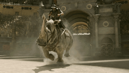 a man is riding a rhino in an arena with the word gladiator on the bottom