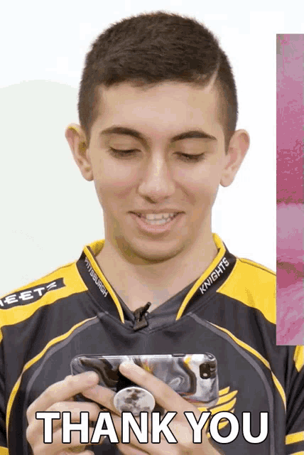 a man wearing a knights shirt holds a cell phone