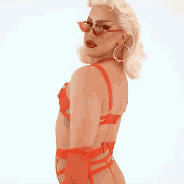 a woman in a red bra and hoop earrings is wearing sunglasses .