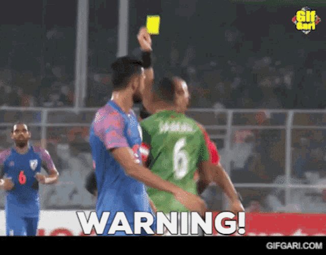 a soccer player with the number 6 on his shirt is getting a yellow card from a referee