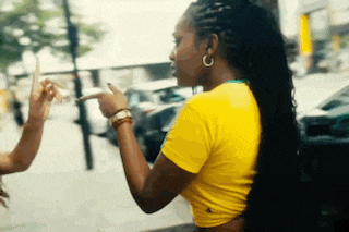 a woman in a yellow shirt is pointing at another woman 's hand .