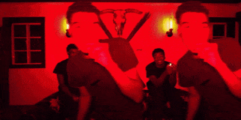 a man is standing in a dark room with a red light behind him .