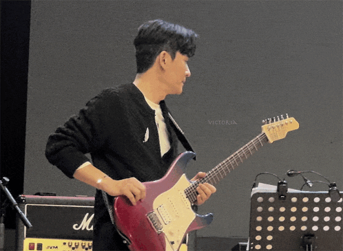 a man is playing a guitar in front of a marshall amplifier
