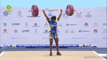 a woman is lifting a barbell in front of a sign that says 2014