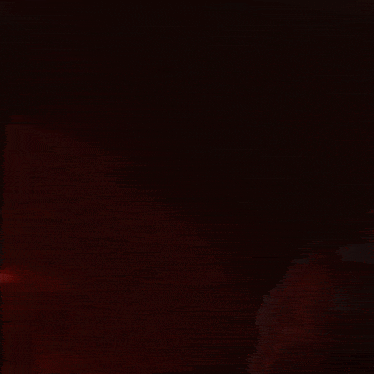a person is standing in the dark with a red light behind them .