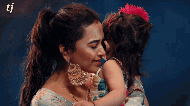 a woman kisses a little girl on the cheek with the letters tj visible