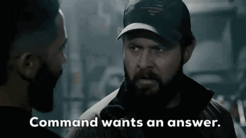 a man with a beard wearing a hat is talking to another man with the words `` command wants an answer '' .