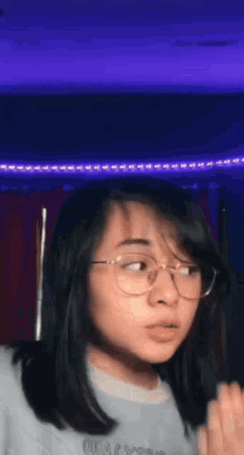 a young girl wearing glasses and a white shirt is making a funny face .