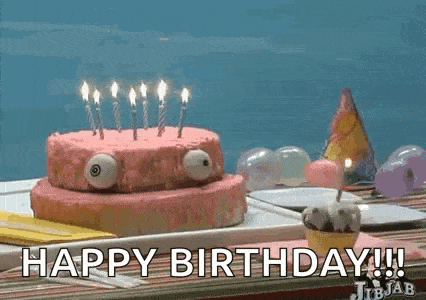 a birthday cake with candles on it is sitting on a table with the words `` happy birthday '' written on it .
