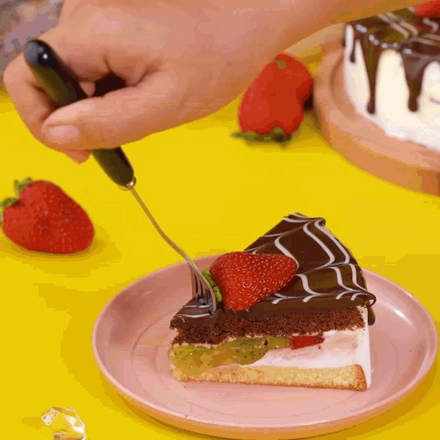 a person is cutting a slice of cake with strawberries on top