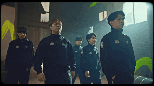 a group of young men are standing in a dark room and one of their shirts says ' squid game ' on the back