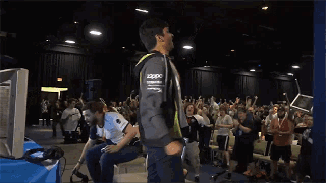 a man wearing a hoodie that says ' uta ' on it stands in front of a crowd