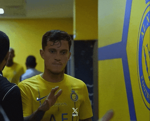 a man wearing a yellow shirt that says roya giving a peace sign