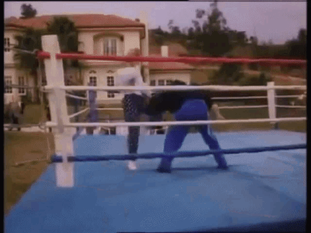 two men are fighting in a boxing ring outside