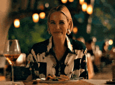 a woman is sitting at a table with a plate of food and wine .