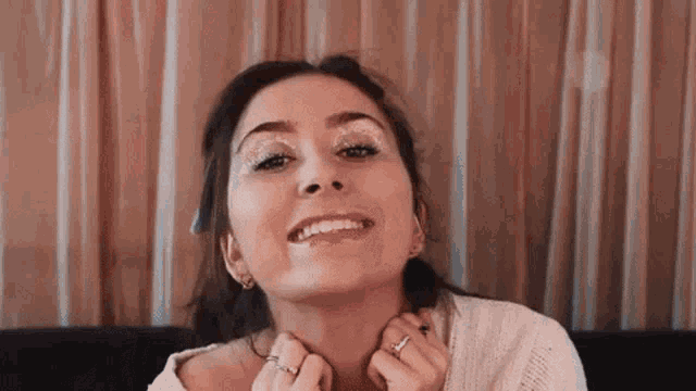 a woman is smiling and touching her neck while wearing glitter on her face .