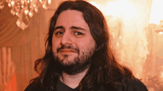 a man with long hair and a beard is looking at the camera