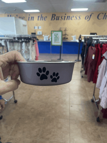 a person holding a dog bowl in front of a sign that says " we in the business of clothes "