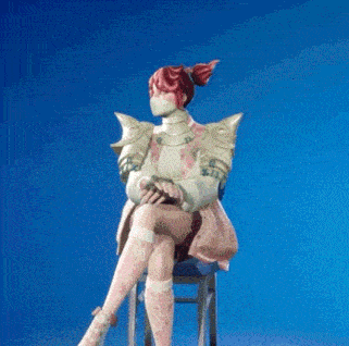 a woman in a pink dress is sitting on a chair with her legs crossed .