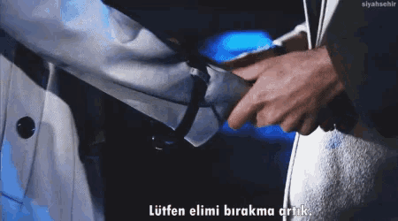 a man in a white coat is holding another man 's hand and says " lütfen elimi birakma arik "