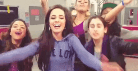 a group of young women are standing next to each other with their arms outstretched and laughing .