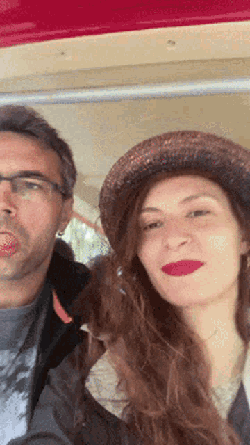 a man and a woman are posing for a picture with the woman wearing a hat