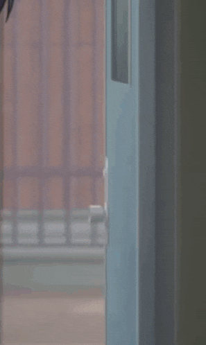 a girl with brown hair and blue eyes is peeking out from behind a door .