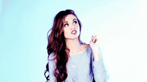 a woman with long hair is wearing a blue sweater and looking up at the sky .