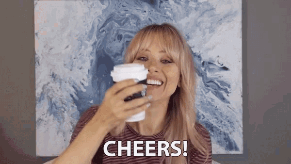 a woman holding a cup of coffee with cheers written on the bottom