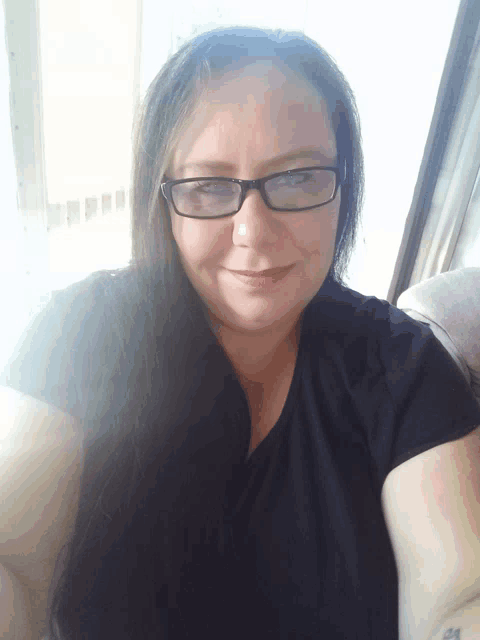 a woman wearing glasses and a black shirt is smiling for the camera