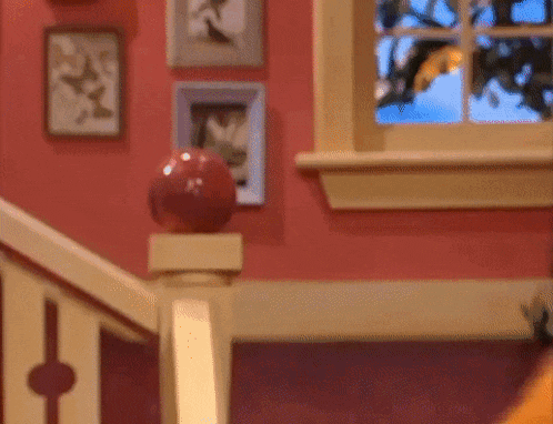 a staircase with a red ball on the railing and a window