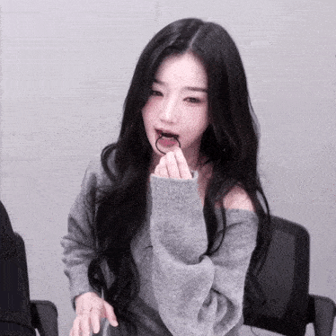 a woman with long black hair wearing a grey sweater