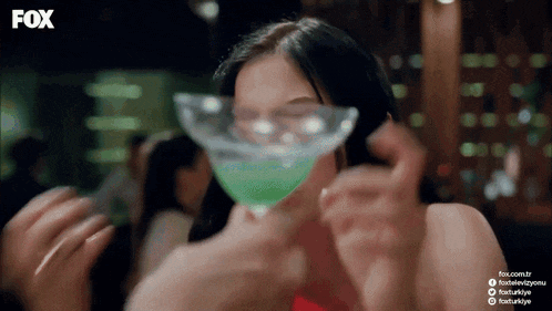 a woman drinking from a martini glass with fox written on the bottom of the screen